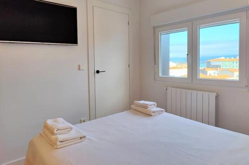 um quarto branco com uma cama e 2 toalhas em Vistas, recién reformado, 2 dormitorios dobles. em Santander