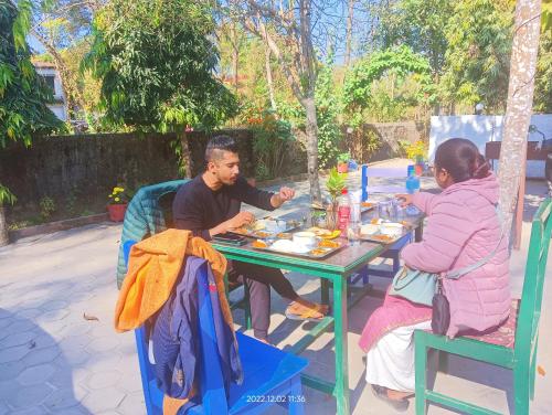 two people sitting at a table eating food at Hotel Butterfly - Peaceful Garden for Nature Lovers in Sauraha