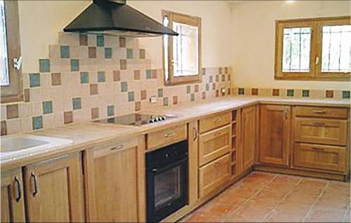 La cuisine est équipée de placards en bois et d'un four avec plaques de cuisson. dans l'établissement Amazing Home In Gonfaron With Outdoor Swimming Pool, à Gonfaron