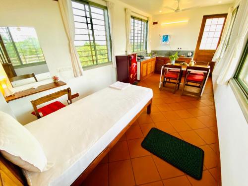 1 dormitorio con 1 cama y cocina con mesa en The Canopy Guest House en Auroville