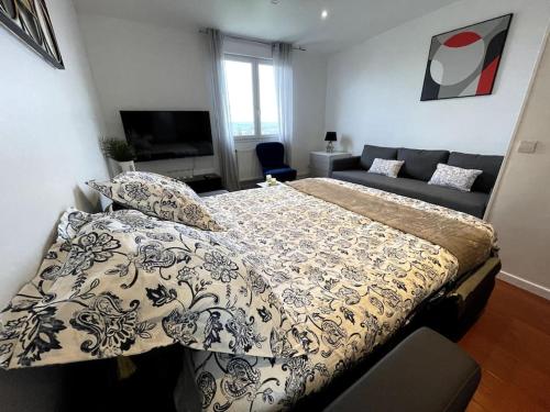 een slaapkamer met een bed en een bank bij Logement très cosy en plein centre-ville in Saint-Cyr-lʼÉcole