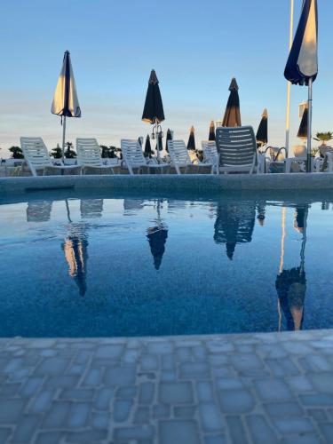 a swimming pool with chairs and umbrellas and the water at Hotel Anthony in Lido di Jesolo