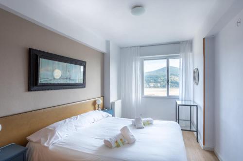 1 dormitorio con 1 cama con sábanas blancas y ventana en El Mirador de Urdaibai, en Busturia