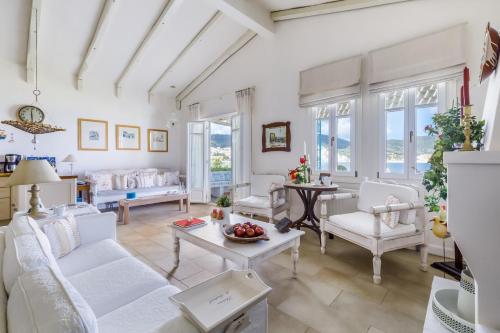 a living room with white furniture and windows at Skopelos Village Hotel in Skopelos Town