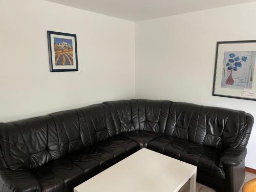 a black leather couch in a living room with a white table at Monteurunterkunft Langenhorst in Groß Niendorf