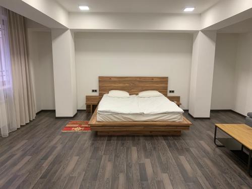 a bedroom with a bed with a wooden headboard at One Day Hotel in Yerevan