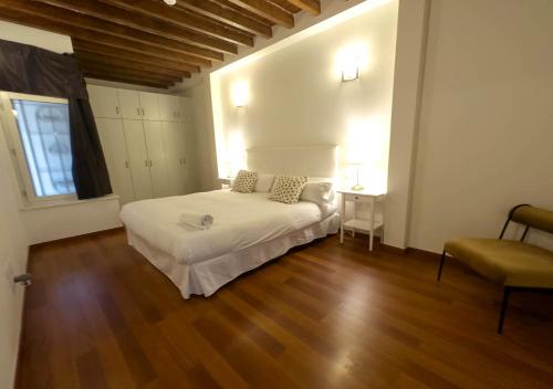 a bedroom with a white bed and a wooden floor at ISA Granada in Granada
