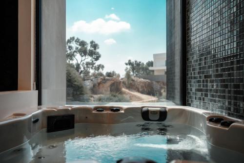 a bath tub in a room with a window at Periyiali Konnos Villas Beach Resort in Protaras