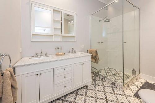 a white bathroom with a sink and a shower at Kerrisdale Bowral in Bowral
