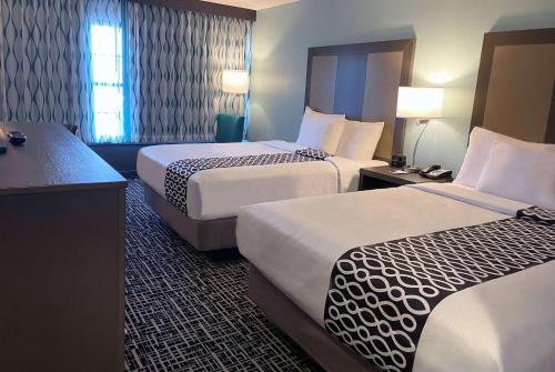 a hotel room with two beds and a desk at La Quinta by Wyndham Jonesboro in Jonesboro