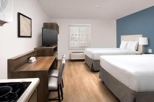 um pequeno quarto de hotel com duas camas e uma cozinha em WoodSpring Suites Chicago Tinley Park em Tinley Park