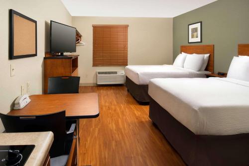 a hotel room with two beds and a desk at WoodSpring Suites Chicago Romeoville in Romeoville