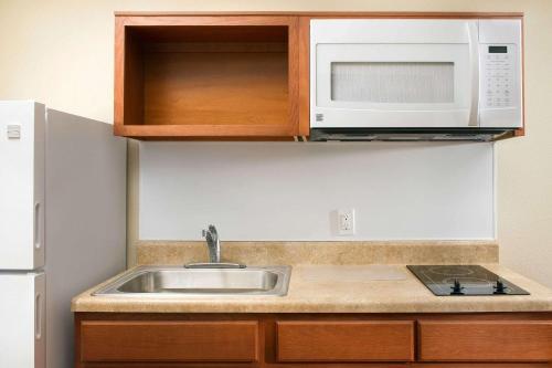 a kitchen with a sink and a microwave at WoodSpring Suites Chicago Romeoville in Romeoville