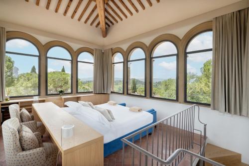 a bedroom with a bed and a bunch of windows at Tenuta Di Sticciano in Certaldo