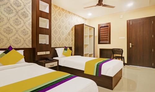 a hotel room with two beds and a chair at Itsy Hotels Sapphire Residency in Manjeri