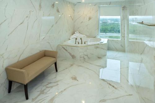Baño de mármol blanco con banco y lavabo en Halifax Tower Hotel & Conference Centre, Ascend Hotel Collection, en Halifax