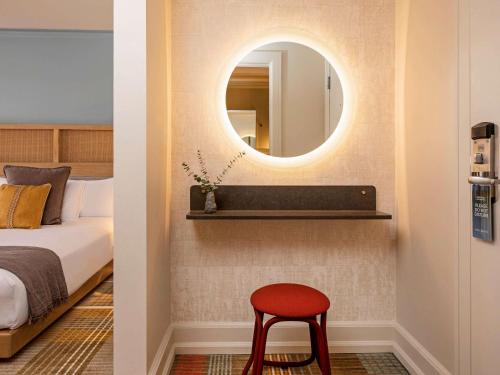 a bedroom with a mirror and a red stool at Hotel Andra Seattle MGallery Hotel Collection in Seattle
