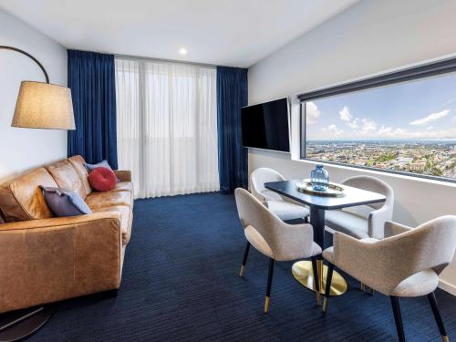 a living room with a couch and a table with chairs at Avani Melbourne Jazz Corner Residences in Melbourne