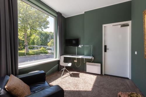 - un salon avec un bureau et une fenêtre dans l'établissement Hotel Leeuwerik, à Bad-Nieuweschans