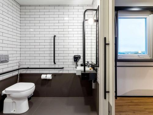 a bathroom with a toilet and a sink and a window at Ibis Aruja in Arujá