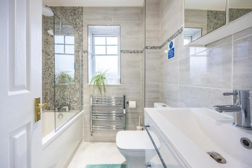 a white bathroom with a toilet and a sink at The Lake Hub in Goodmayes