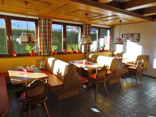 a restaurant with tables and chairs and windows at Sportpension Christina by PiaundDirk in Fügen