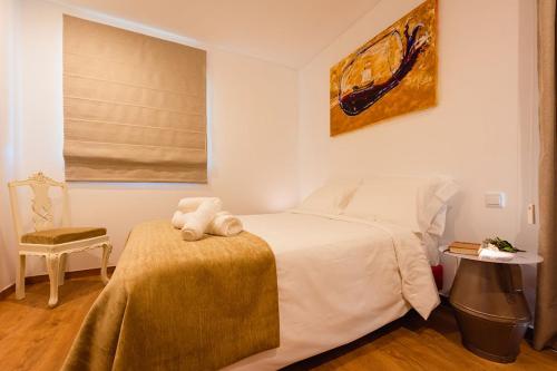 a bedroom with a white bed and a chair at Gamboas Place in Olhalvo