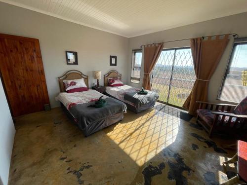 a bedroom with two beds and a large window at Raptor's View Dullstroom in Dullstroom