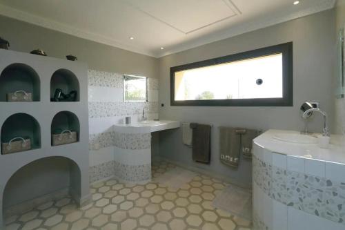 baño con 2 lavabos, bañera y ventana en Villa Pepe, en El Harkat