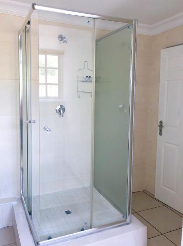 a shower with a glass door in a bathroom at Blue Crane Guesthouse in Maseru