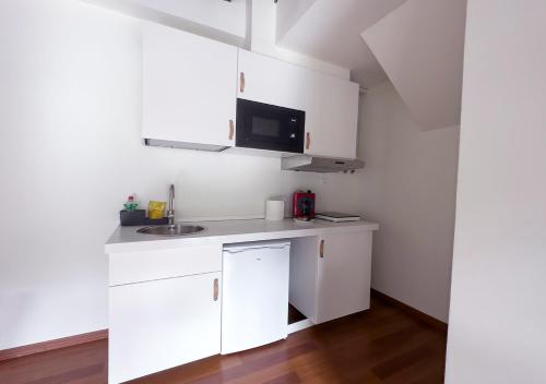 a white kitchen with a sink and a microwave at ISA Granada in Granada