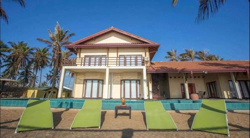 een huis met een zwembad en stoelen ervoor bij Reef Bungalow Hotel in Pamunugama