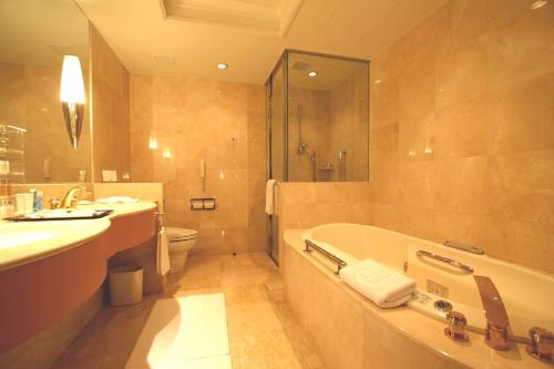 a bathroom with a tub and a sink and a toilet at Grand Park Otaru in Otaru