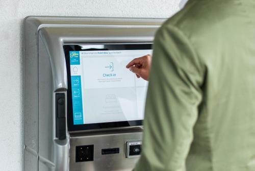 a man is pointing at an atm machine at Tailormade Hotel IDEA Spreitenbach in Spreitenbach