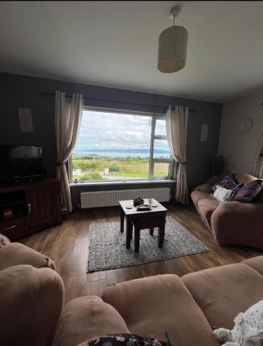 a living room with a table and a large window at Rosie's Cottage in Moville