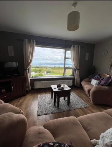 uma sala de estar com uma mesa e uma grande janela em Rosie's Cottage em Moville