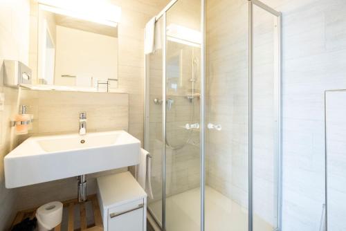 a bathroom with a sink and a shower at Tailormade Hotel IDEA Spreitenbach in Spreitenbach