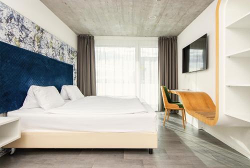 Schlafzimmer mit einem weißen Bett und einem Schreibtisch in der Unterkunft Tailormade Hotel IDEA Spreitenbach in Spreitenbach