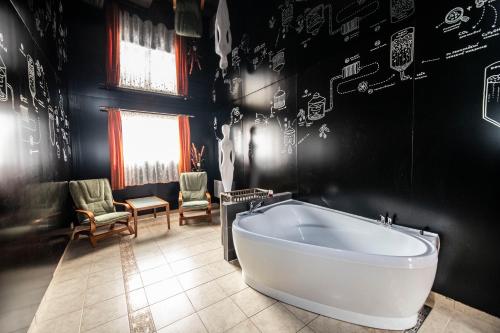 的住宿－LIONS Nesuchyně，浴缸位于带黑色墙壁的房间内