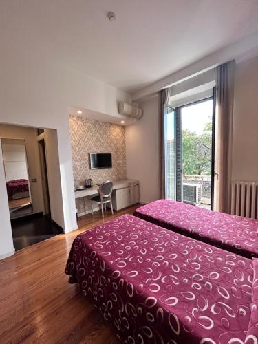 a bedroom with a large bed with a pink bedspread at Hotel Aspromonte in Milan
