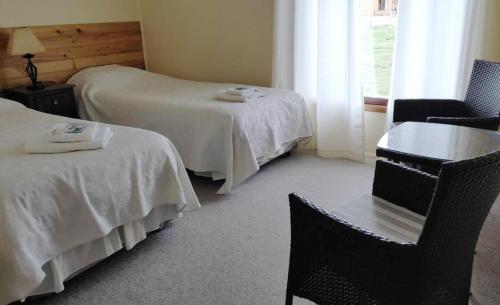 a hotel room with two beds and a table and chairs at Hosteria Lago del Toro in Torres del Paine