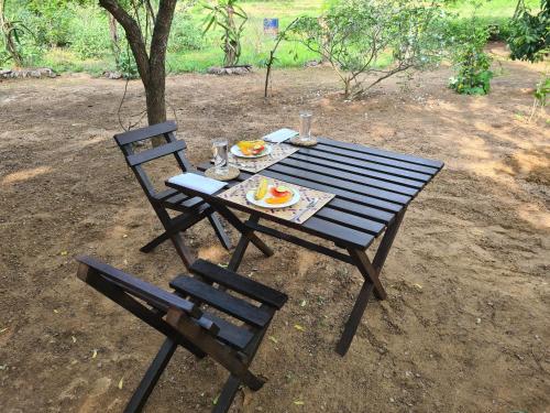 a picnic table with a plate of food and two chairs at Ranakeliya Lodge - Yala in Yala