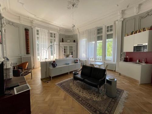 - un grand salon avec une chaise et un canapé dans l'établissement Suite Célestine Palace Excelsior vue lac, à Aix-les-Bains