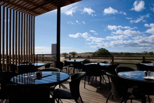 ein Restaurant mit Tischen und Stühlen auf einer Terrasse in der Unterkunft Algarve Apartment Manta Rota in Vila Nova De Cacela