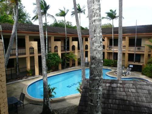 a view of a hotel with a swimming pool and palm trees at Oasis Inn Apartments in Cairns