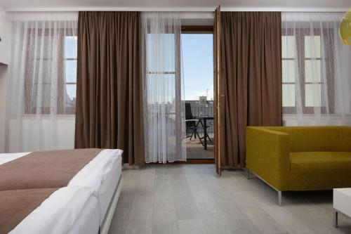 OREA Hotel Arigone Olomouc في أولوموك: غرفه فندقيه بسرير وكرسي اصفر