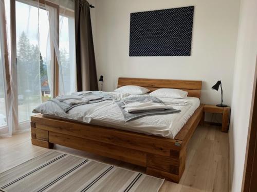 ein Holzbett in einem Schlafzimmer mit einem großen Fenster in der Unterkunft Apartmán Kubínska 33 in Dolný Kubín