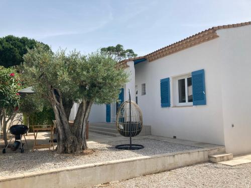 a house with a tree and a bird cage next to a building at Belle villa spacieuse avec piscine privée, 10 couchages,wifi, proche canal du midi et à 3 km de la mer LXPIN7 in Portiragnes
