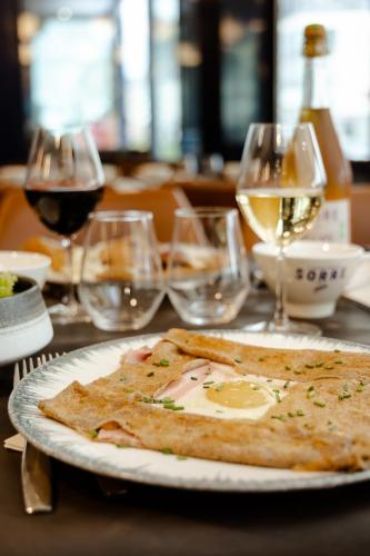 a plate with a slice of pizza on a table with wine glasses at La Marinière Hôtel Restaurant in Saint Malo