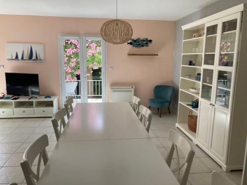 una sala da pranzo con tavolo e sedie bianchi di Belle villa spacieuse avec piscine privée, 10 couchages,wifi, proche canal du midi et à 3 km de la mer LXPIN7 a Portiragnes